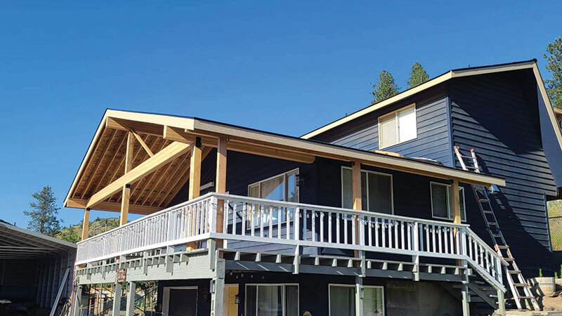 Completed navy timber-frame custom home with wraparound deck built by Gitter Done Construction in Eastern Washington