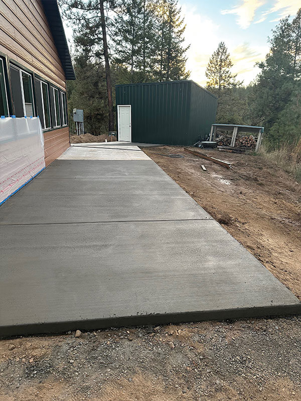 New concrete driveway poured in front of a green shop by Gitter Done Construction in Eastern Washington