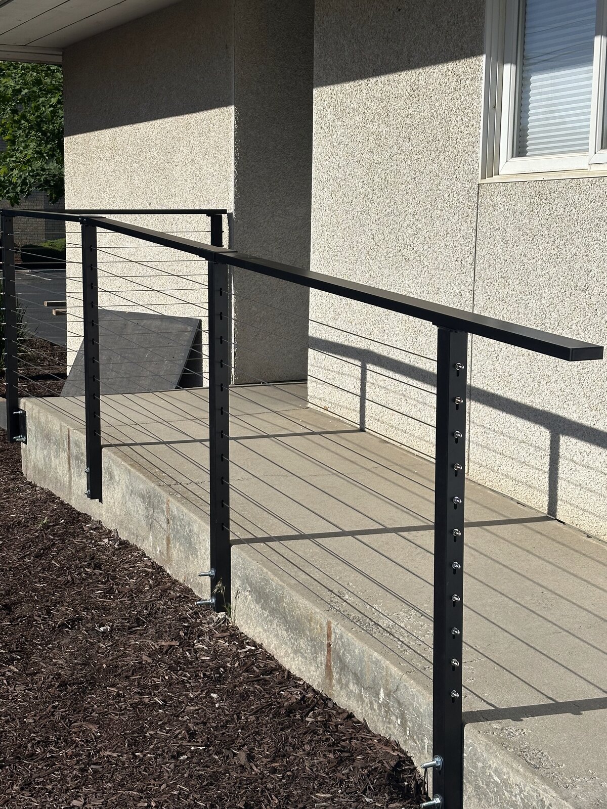 Custom black cable railing installed by Gitter Done Construction along an existing ramp