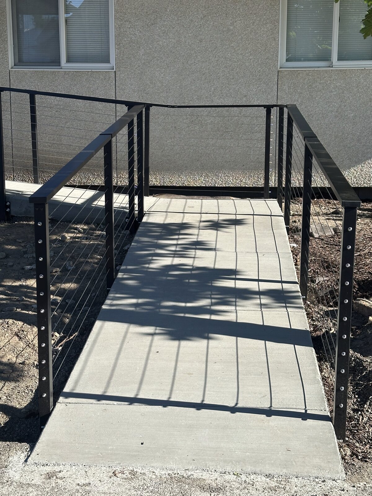 Poured concrete walkway ramp with cable railings on both sides by Gitter Done Construction